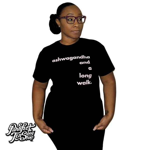 A woman wearing a black short-sleeve t-shirt with the white text 'ashwagandha and a long walk.' printed on the front.